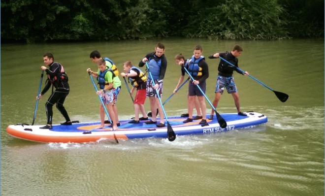 Groupe de pagayeurs sur un stand-up paddle collectif sur la rivière